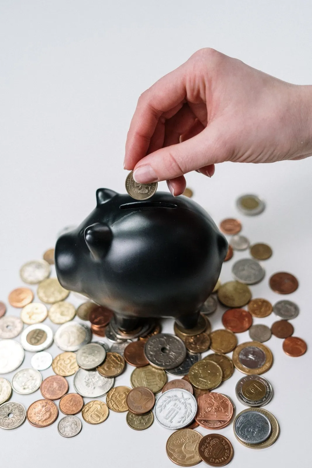 Mano metiendo una moneda en una hucha, ahorro en la factura de la luz
