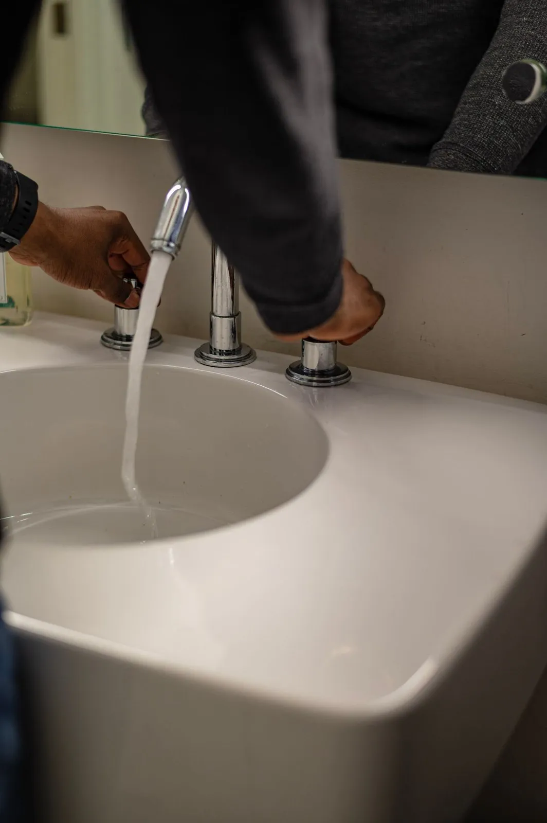Persona abriendo un grifo de agua en el lavabo de su casa