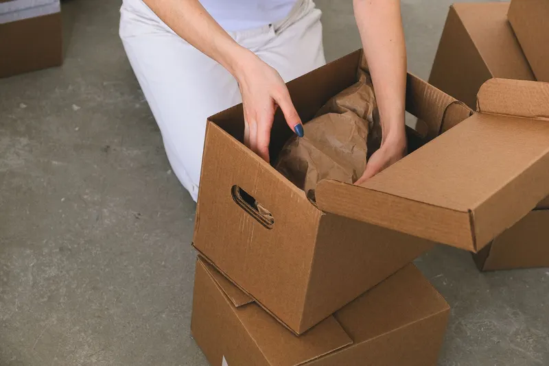 Persona embalando objetos en una caja de cartón para una mudanza en Córdoba