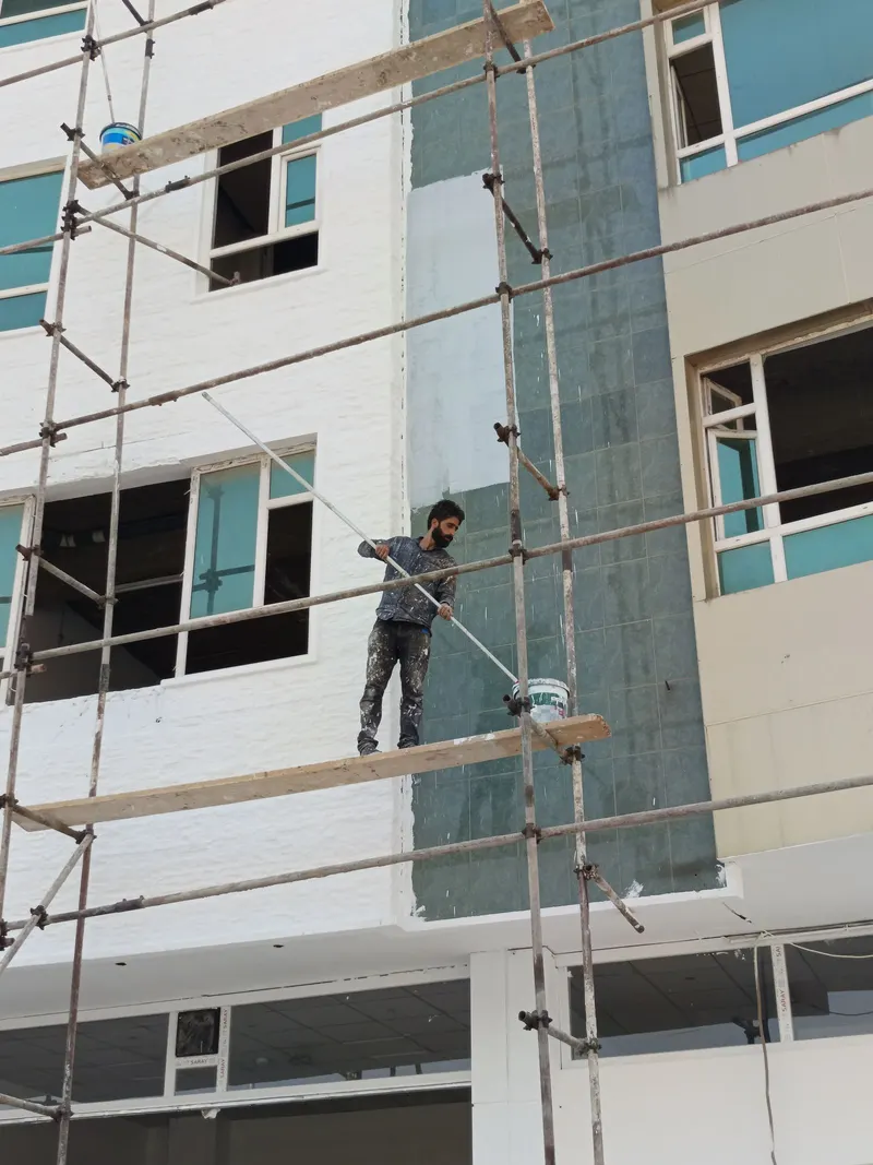 Pintor de fachadas trabajando en un andamio en Córdoba